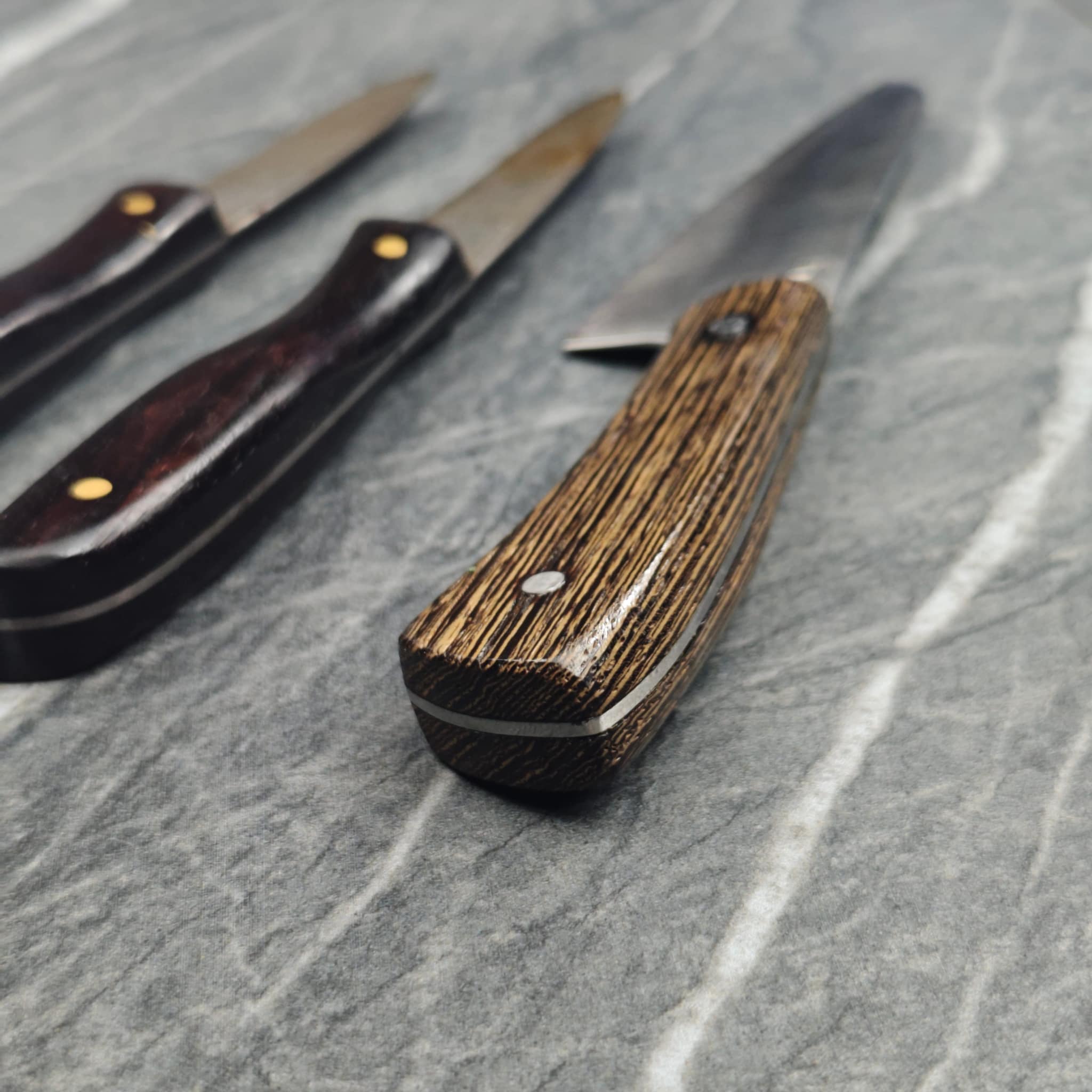 Wooden-handled folding knife with exotic wood pattern and brass rivets