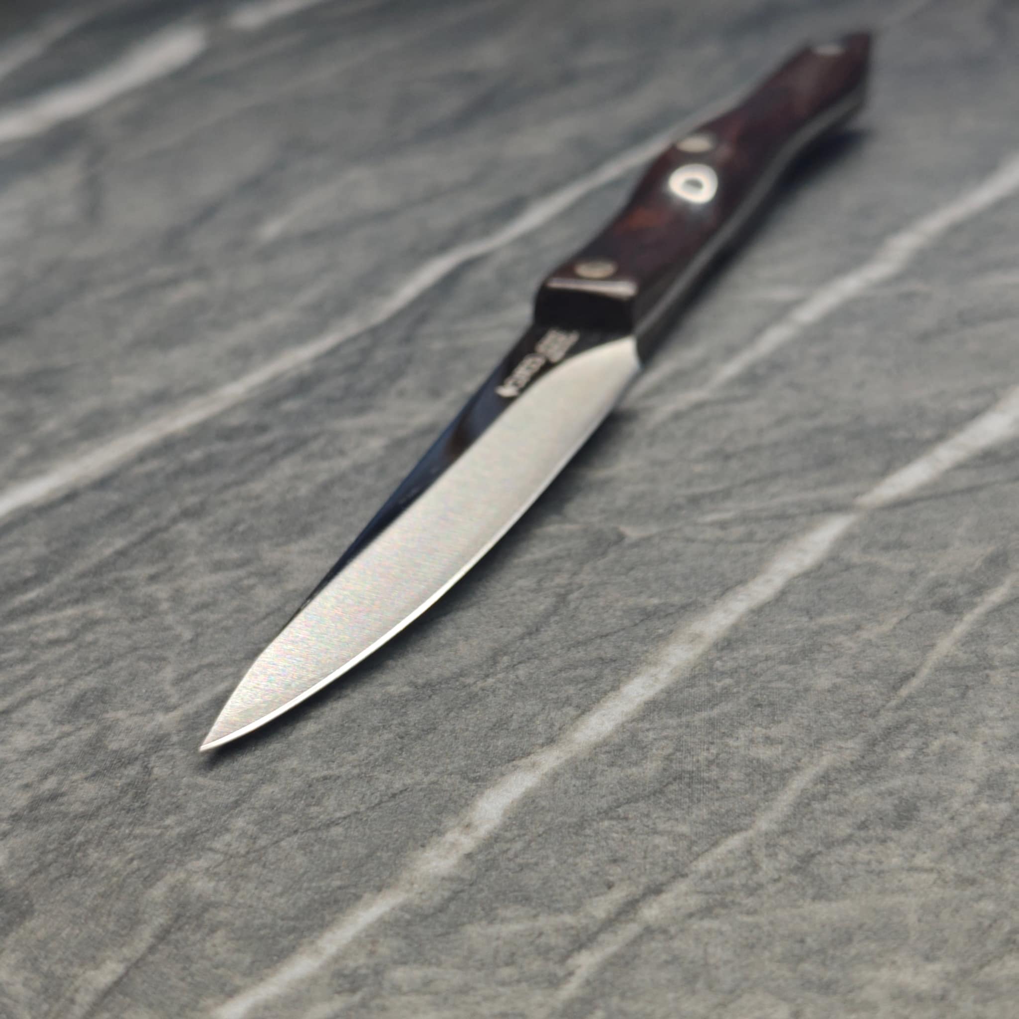 Multiple sharpened knives arranged on dark surface