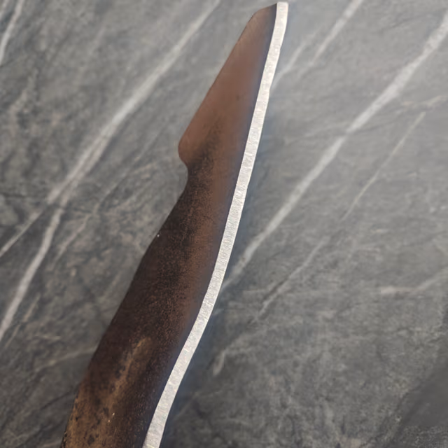 Sharpened mower blade close-up showing a polished razor-sharp cutting edge after professional sharpening