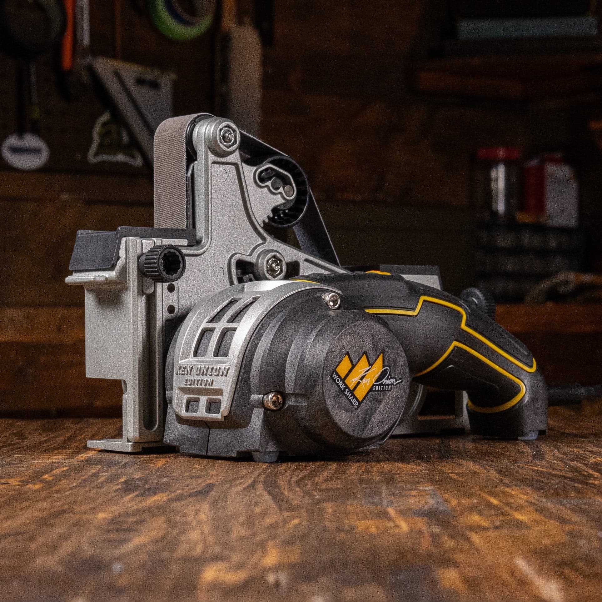 Work Sharp Ken Onion Edition MK2 belt grinder sharpener on a dark wood workbench in a professional sharpening workshop