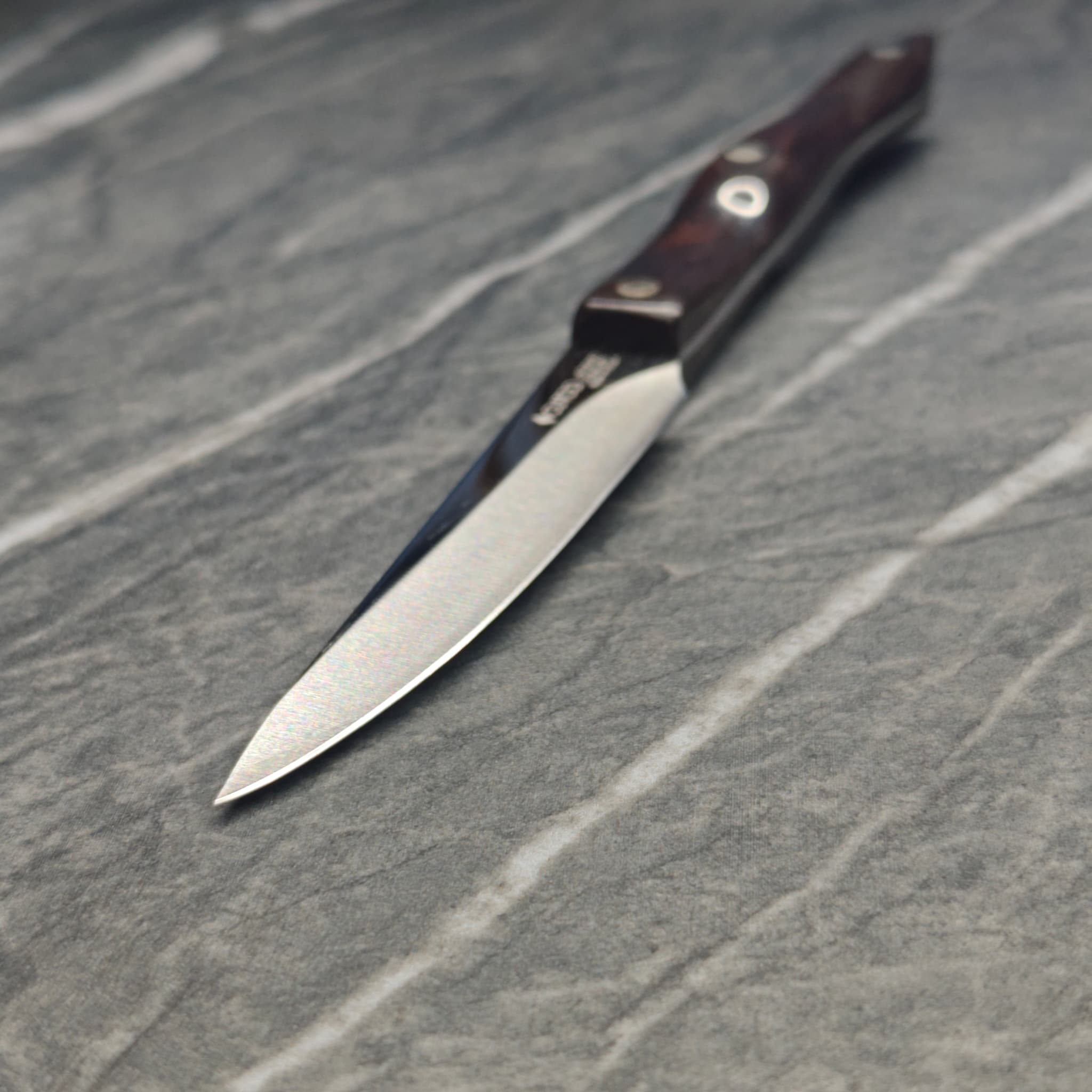 Multiple sharpened knives arranged on dark surface
