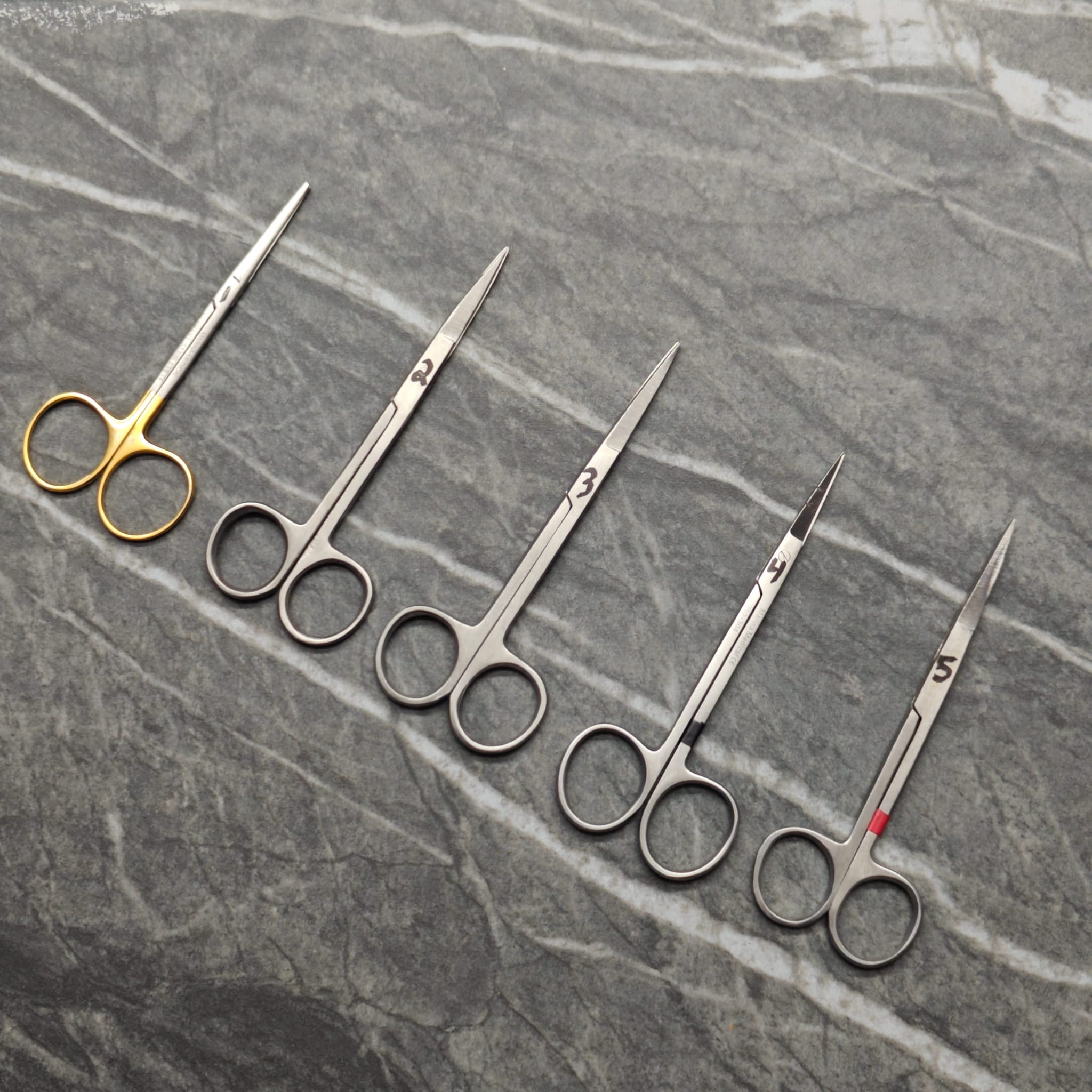 Precision scissors with gold and silver finishes arranged on cutting mat