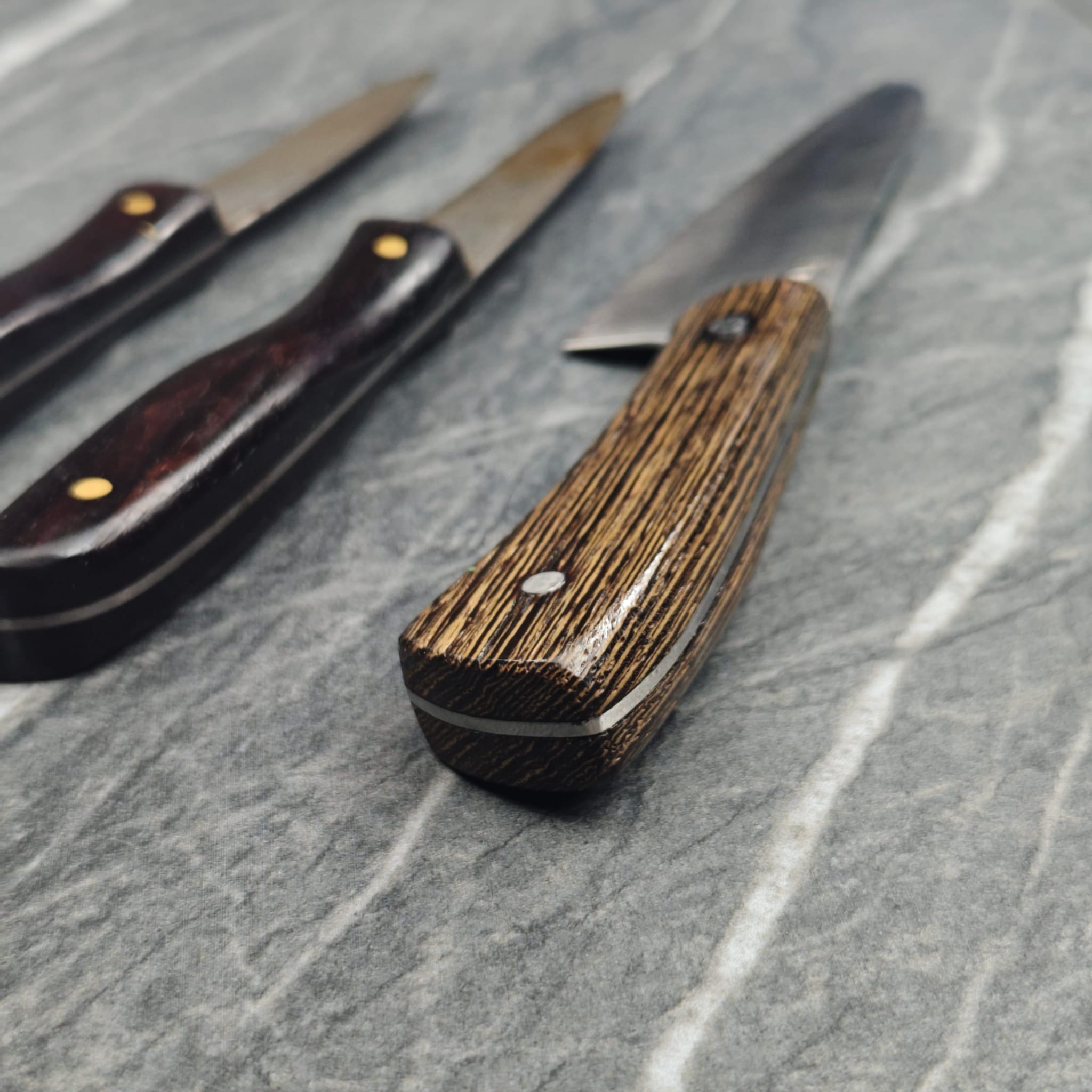 Wooden-handled folding knife with exotic wood pattern and brass rivets