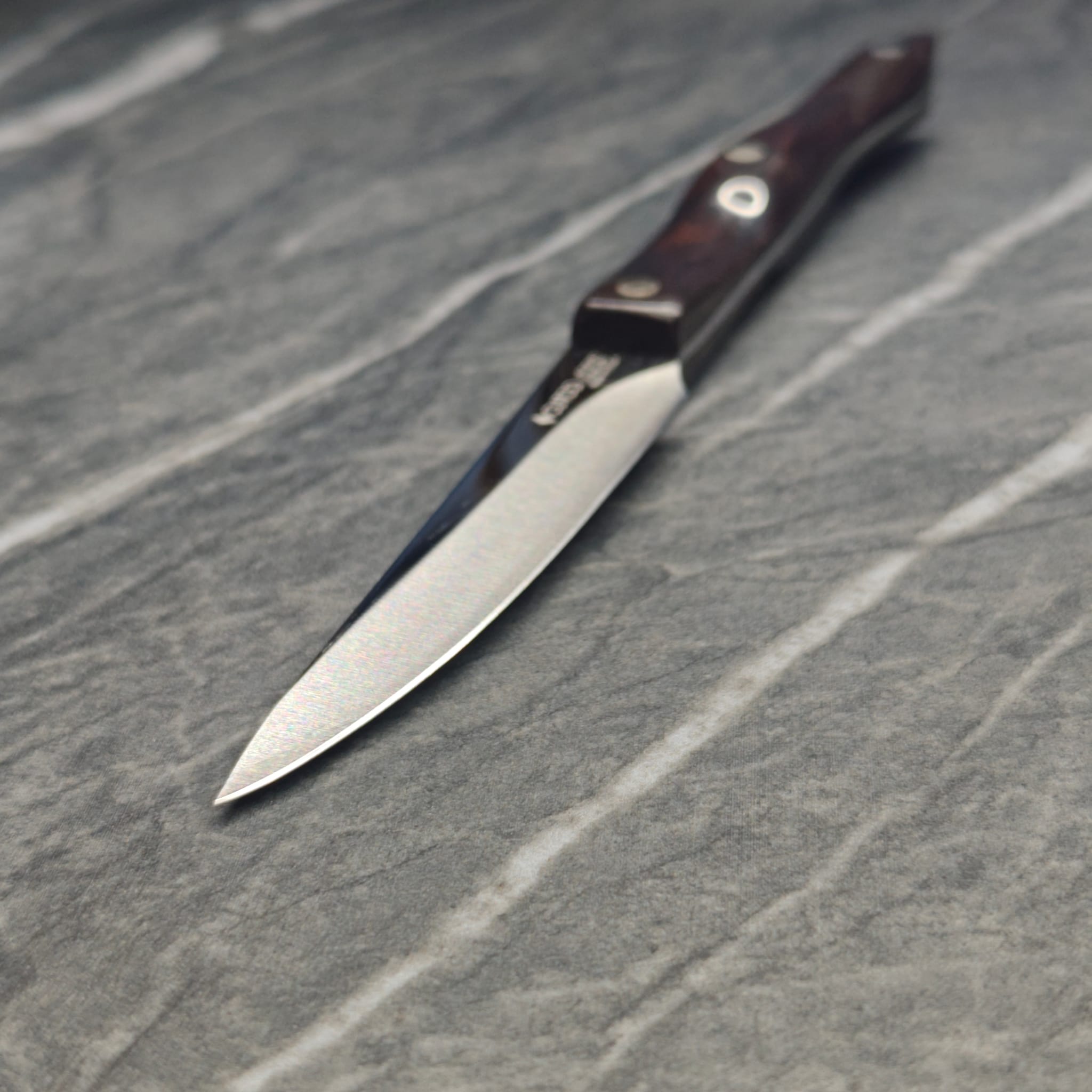 Multiple sharpened knives arranged on dark surface