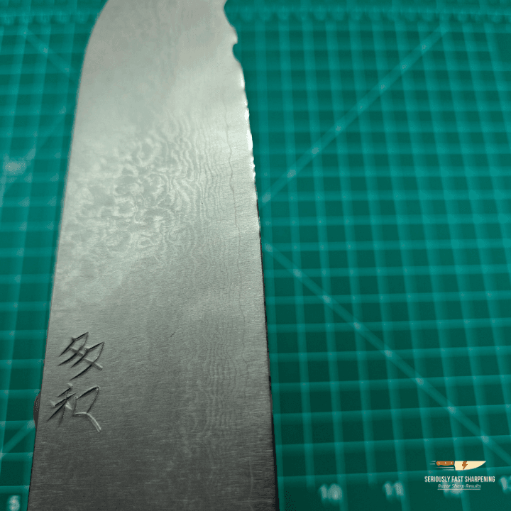 Professional Santoku knife sharpening showing razor-sharp Japanese blade with Damascus pattern