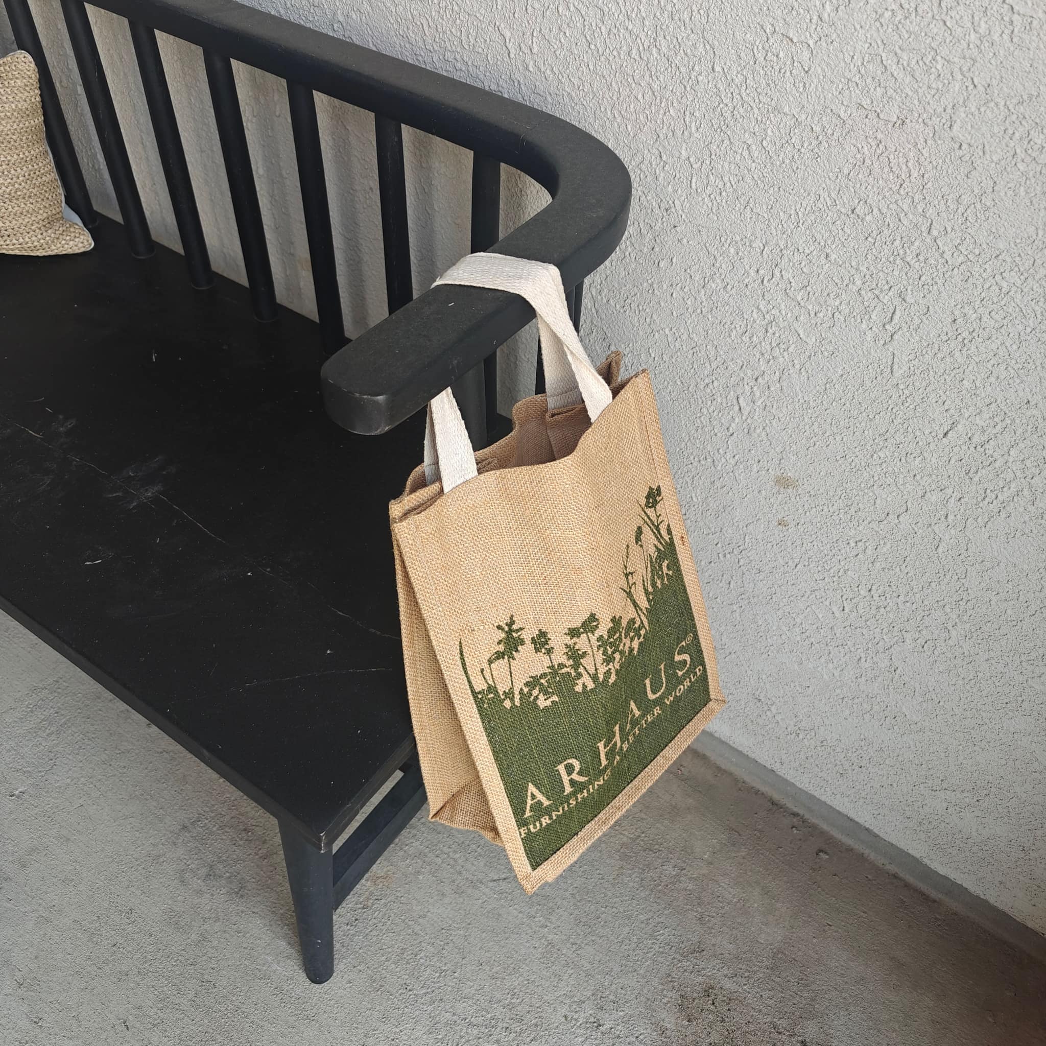 Arhaus jute tote hanging from a porch bench for knife pickup
