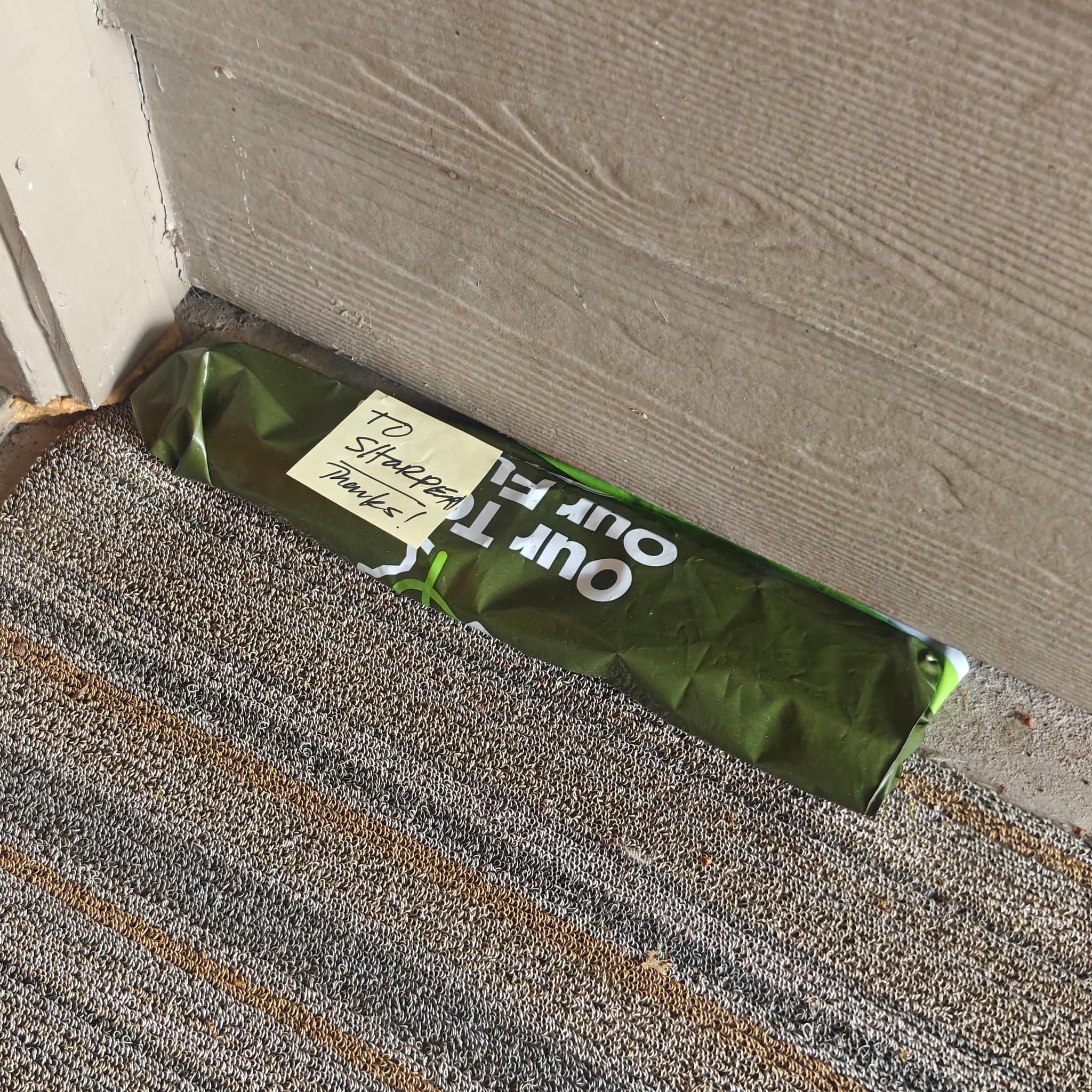 Green SFS bag with sticky note left at doorstep for porch pickup