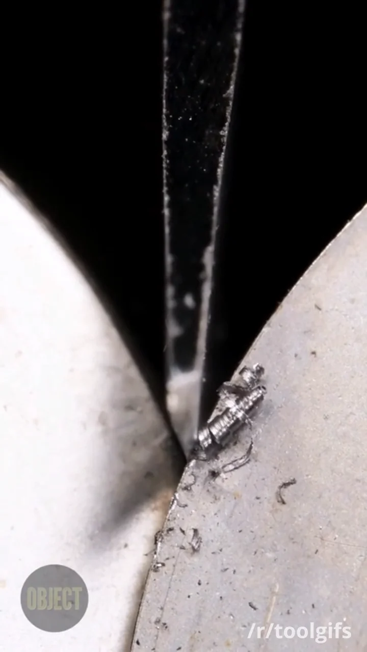 Extreme macro close-up of a knife edge being destroyed by a pull-through sharpener — visible metal swarf curling off the blade