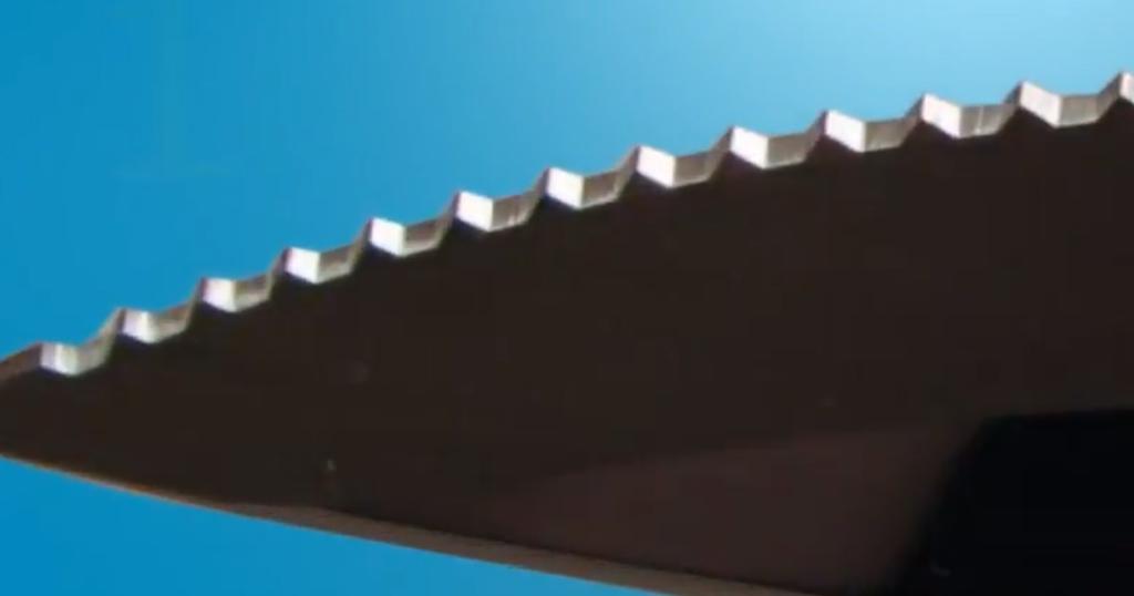 Close-up macro shot of a Cutco Double-D edge showing the recessed cutting surface and protective crowns against a blue background